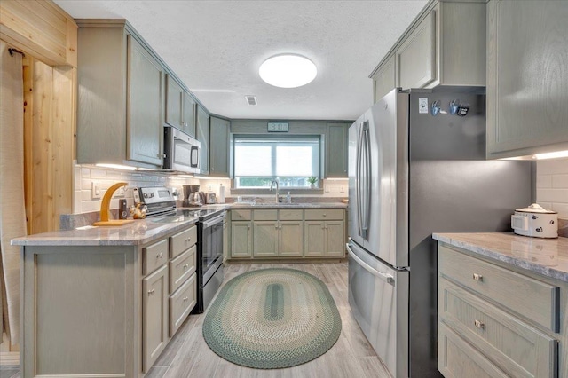 4823 Lakeside Blvd, Hale, MI 48739 - kitchen featuring stainless steel appliances, light wood-type flooring, backsplash, a textured ceiling, and light stone counters