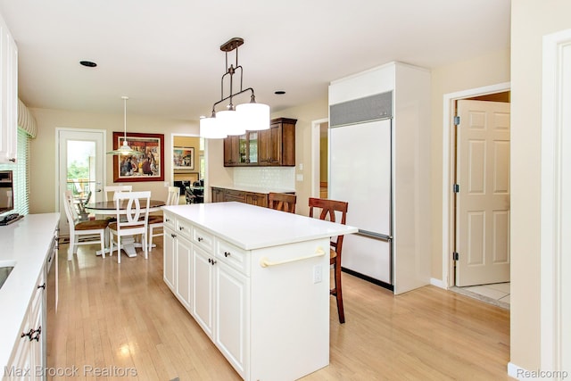 6524 Pleasant Lake Ct, West Bloomfield, MI 48322 - kitchen featuring paneled built in fridge, tasteful backsplash, a breakfast bar, light wood-type flooring, and white cabinetry