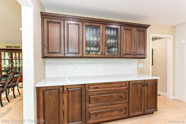 6524 Pleasant Lake Ct, West Bloomfield, MI 48322 - kitchen featuring decorative backsplash, glass insert cabinets, light countertops, and dark brown cabinetry