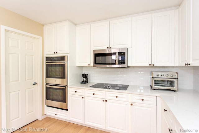 6524 Pleasant Lake Ct, West Bloomfield, MI 48322 - kitchen with appliances with stainless steel finishes, tasteful backsplash, light countertops, white cabinets, and light wood-type flooring