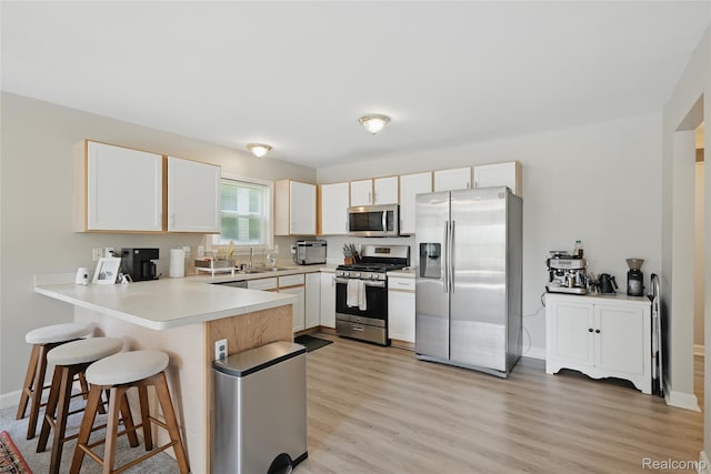 1372 Maryland St, Grosse Pointe, MI 48230 - kitchen with appliances with stainless steel finishes, a peninsula, a breakfast bar area, and light wood finished floors