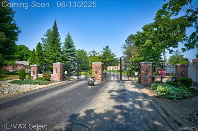 16483 Dawnlight Dr, Fenton, MI 48430 - view of asphalt road with a gate, a gated entry, curbs, and traffic signs