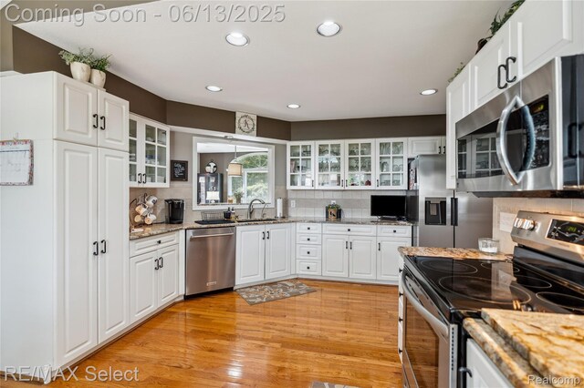 16483 Dawnlight Dr, Fenton, MI 48430 - kitchen with appliances with stainless steel finishes, light wood-style floors, backsplash, glass insert cabinets, and recessed lighting