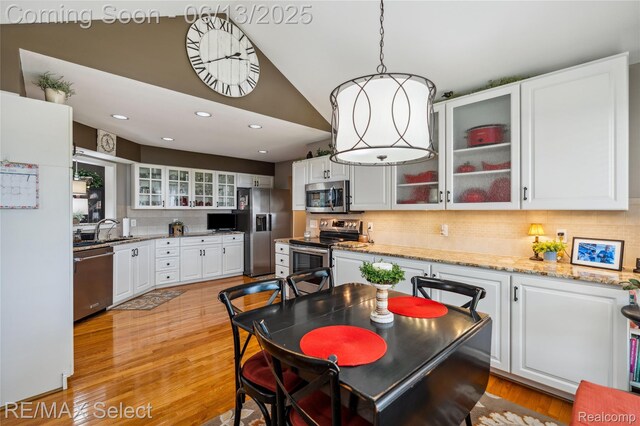 16483 Dawnlight Dr, Fenton, MI 48430 - kitchen featuring appliances with stainless steel finishes, decorative backsplash, white cabinetry, pendant lighting, and light wood-style flooring