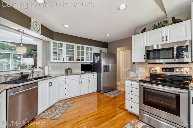 16483 Dawnlight Dr, Fenton, MI 48430 - kitchen with appliances with stainless steel finishes, light wood-style flooring, tasteful backsplash, white cabinetry, and recessed lighting