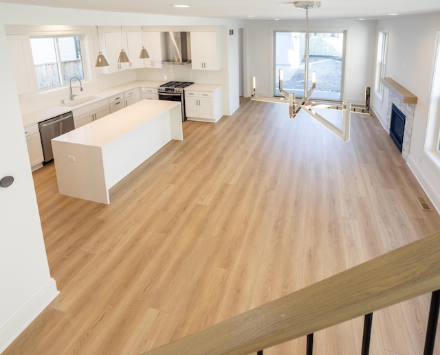 1439 Bennaville Ave, Birmingham, MI 48009 - kitchen featuring appliances with stainless steel finishes, wall chimney range hood, white cabinetry, light countertops, and a kitchen island