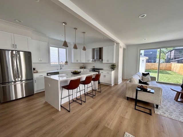 1439 Bennaville Ave, Birmingham, MI 48009 - kitchen with stainless steel appliances, a breakfast bar, wall chimney exhaust hood, white cabinetry, and light wood-type flooring