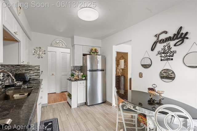 27557 W Echo Vly Unit 153, Farmington Hills, MI 48334 - kitchen with freestanding refrigerator, backsplash, white cabinetry, light wood finished floors, and dark stone countertops