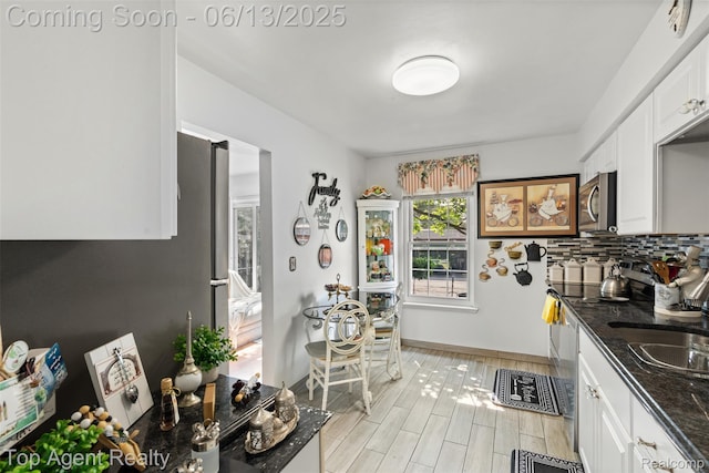 27557 W Echo Vly Unit 153, Farmington Hills, MI 48334 - kitchen with appliances with stainless steel finishes, white cabinets, backsplash, dark stone counters, and light wood finished floors