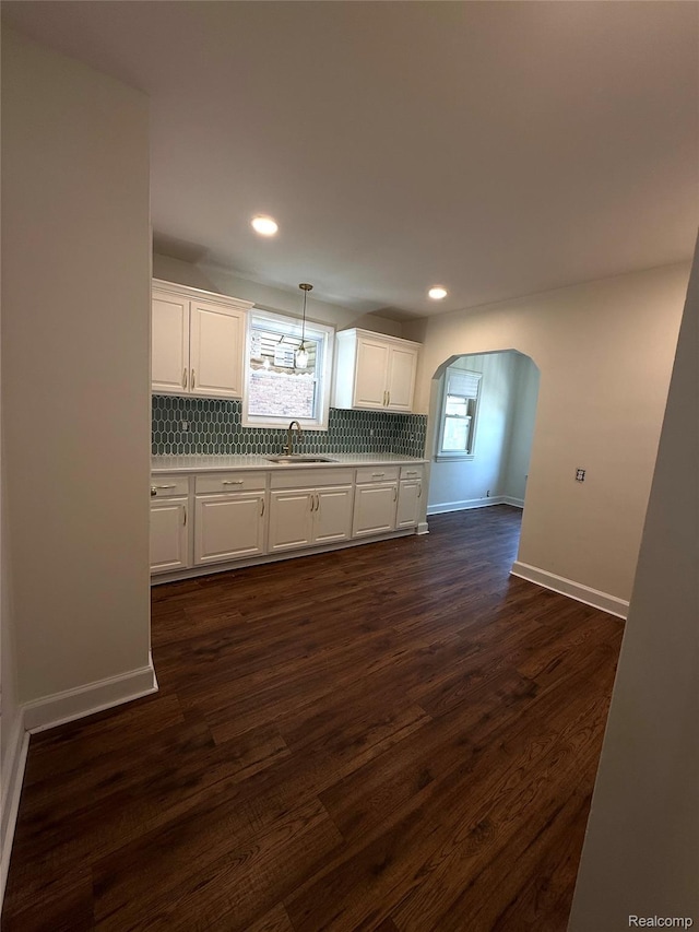 16652 Mendota St, Detroit, MI 48221 - kitchen with arched walkways, decorative backsplash, white cabinets, dark wood-style flooring, and light countertops