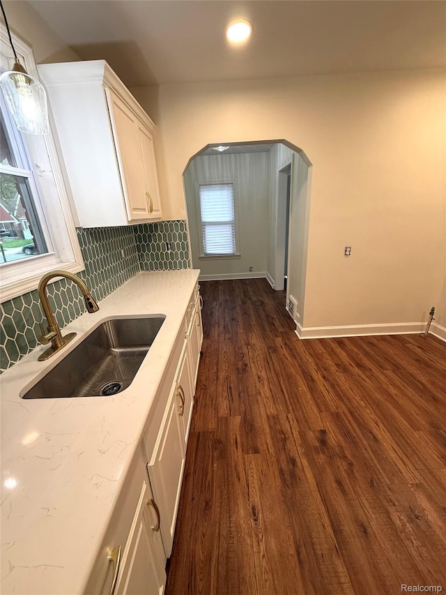 16652 Mendota St, Detroit, MI 48221 - kitchen with white cabinets, decorative backsplash, dark wood-type flooring, arched walkways, and light stone countertops