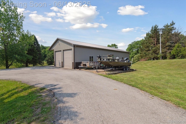 2970 Sand Beach Rd, Bad Axe, MI 48413 - view of front of property featuring a detached garage, a front yard, an outbuilding, and a metal roof