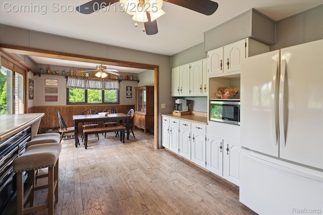 2970 Sand Beach Rd, Bad Axe, MI 48413 - kitchen with freestanding refrigerator, ceiling fan, stainless steel microwave, a wainscoted wall, and light wood-style flooring