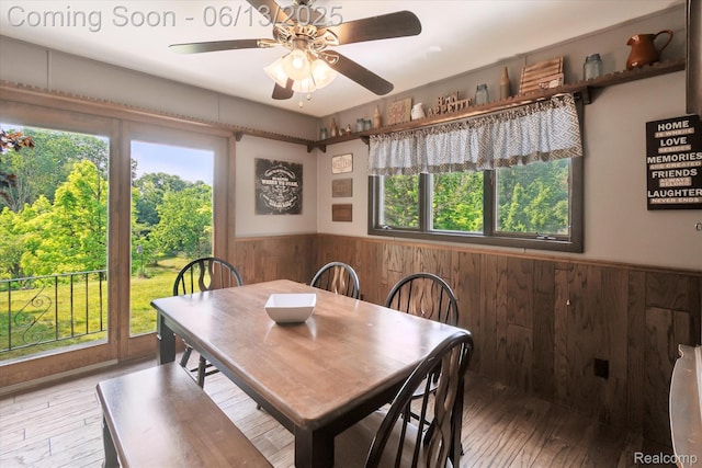 2970 Sand Beach Rd, Bad Axe, MI 48413 - dining area with wainscoting, wood walls, wood-type flooring, and ceiling fan