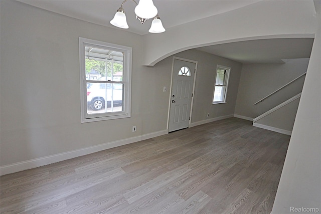 19444 Inkster Rd, Redford, MI 48240 - foyer featuring arched walkways, a chandelier, wood finished floors, stairs, and baseboards