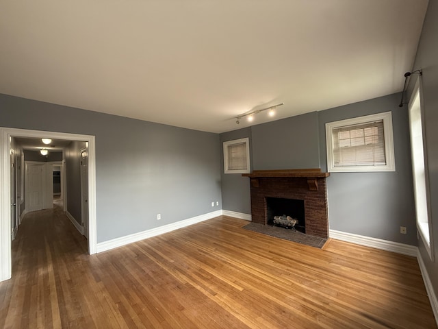 469 W Willis St Unit 4, Detroit, MI 48201 - unfurnished living room featuring a brick fireplace, wood finished floors, baseboards, and track lighting