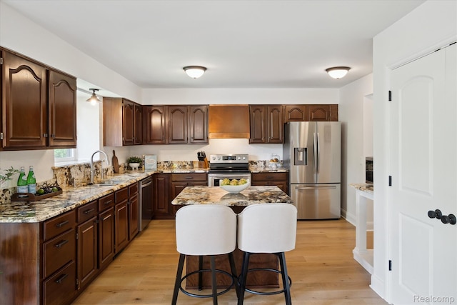 5695 Deerwood, Commerce Twp, MI 48382 - kitchen with stainless steel appliances, premium range hood, light wood-type flooring, light stone countertops, and dark brown cabinetry