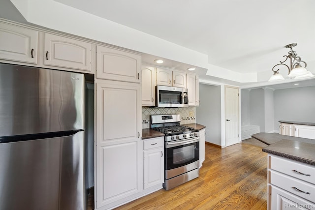 7302 Parkway Ct, Canton, MI 48187 - kitchen featuring stainless steel appliances, dark countertops, backsplash, light wood-style floors, and decorative light fixtures