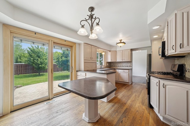 7302 Parkway Ct, Canton, MI 48187 - kitchen with stainless steel range with gas stovetop, dark countertops, tasteful backsplash, light wood finished floors, and recessed lighting