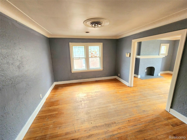 16612 Ilene St, Detroit, MI 48221 - unfurnished room with hardwood / wood-style flooring, a fireplace with flush hearth, a textured wall, and crown molding
