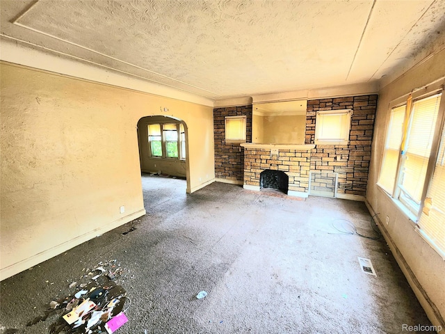 16612 Ilene St, Detroit, MI 48221 - unfurnished living room featuring arched walkways, a fireplace, and a textured ceiling