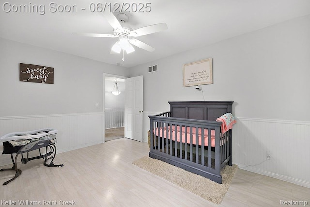 46341 Jasmine Ct, Chesterfield, MI 48047 - bedroom with wainscoting, wood finished floors, ceiling fan, and a crib