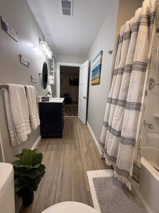 4223 S Harvard Ave, Baldwin, MI 49304 - full bathroom featuring vanity, hardwood / wood-style flooring, shower / tub combo, baseboards, and toilet