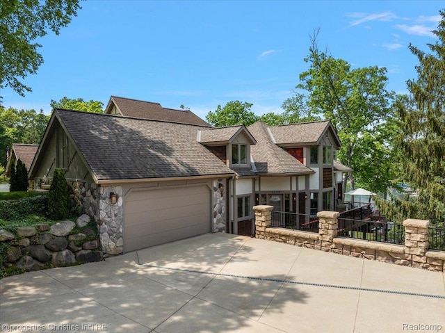 1739 Ridge Rd, White Lake, MI 48383 - tudor home featuring stone siding, a garage, driveway, and roof with shingles