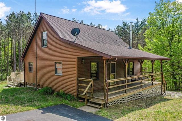 2460 E 26th Rd, Cadillac, MI 49601 - view of side of home with a lawn, covered porch, and roof with shingles
