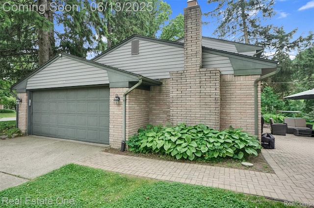23229 Gilbar St, Novi, MI 48375 - view of front of home with brick siding, concrete driveway, a garage, and a chimney