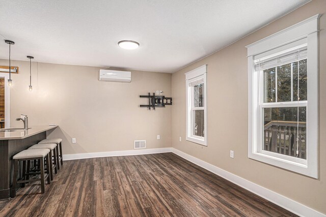 119 E Eliza St, Schoolcraft, MI 49087 - unfurnished dining area featuring a wall mounted air conditioner, dark wood finished floors, baseboards, and a sink