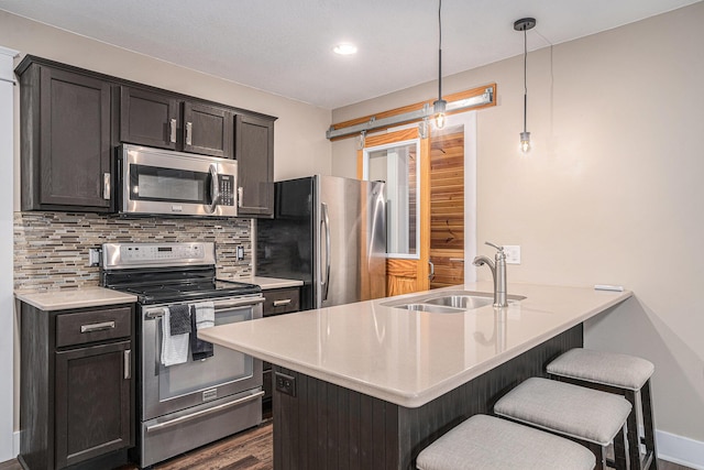 119 E Eliza St, Schoolcraft, MI 49087 - kitchen featuring appliances with stainless steel finishes, a sink, a breakfast bar, decorative backsplash, and dark wood-type flooring