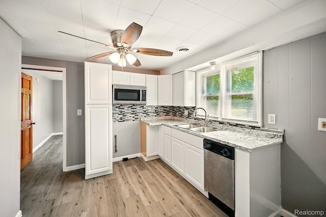 2070 Harwine St, Flint, MI 48532 - kitchen featuring stainless steel appliances, ceiling fan, light wood-style flooring, white cabinetry, and backsplash