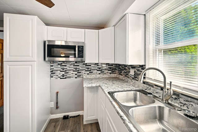 2070 Harwine St, Flint, MI 48532 - kitchen featuring stainless steel microwave, dark wood-type flooring, white cabinets, and decorative backsplash