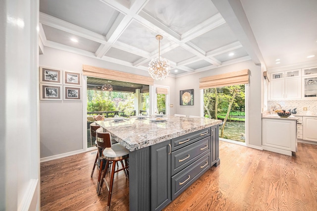 2002 Valleyview Dr, Ann Arbor, MI 48105 - kitchen featuring white cabinets, a breakfast bar area, light wood finished floors, glass insert cabinets, and a kitchen island