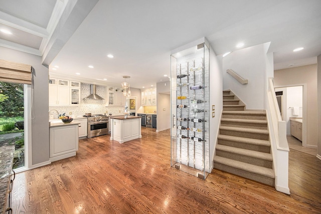 2002 Valleyview Dr, Ann Arbor, MI 48105 - kitchen featuring stainless steel stove, wall chimney exhaust hood, a kitchen island, recessed lighting, and white cabinetry