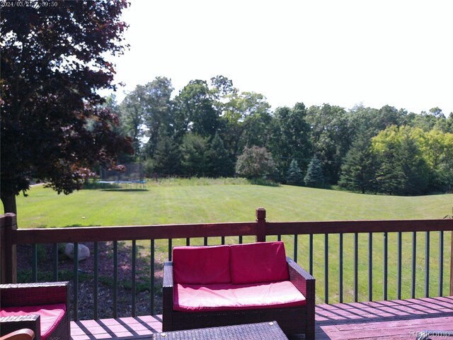 6140 Mcguire Rd, Fenton, MI 48430 - wooden terrace featuring a trampoline, a lawn, and an outdoor living space