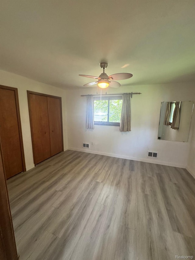 21451 N Nunneley Rd, Shelby Twp, MI 48036 - unfurnished bedroom featuring wood finished floors, two closets, a ceiling fan, and baseboards