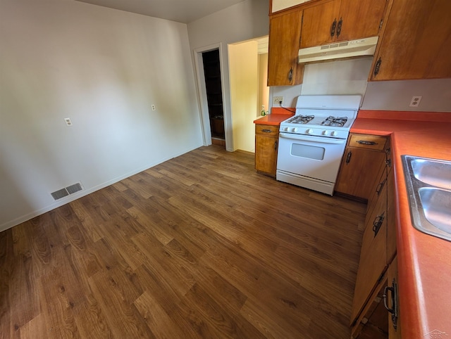 1712 S Hamilton St, Saginaw, MI 48602 - kitchen with under cabinet range hood, white range with gas stovetop, brown cabinetry, and dark wood finished floors
