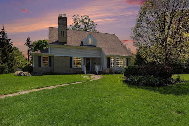 3225 Bronson Blvd, Kalamazoo, MI 49008 - cape cod home with a chimney, a yard, stone siding, and a porch