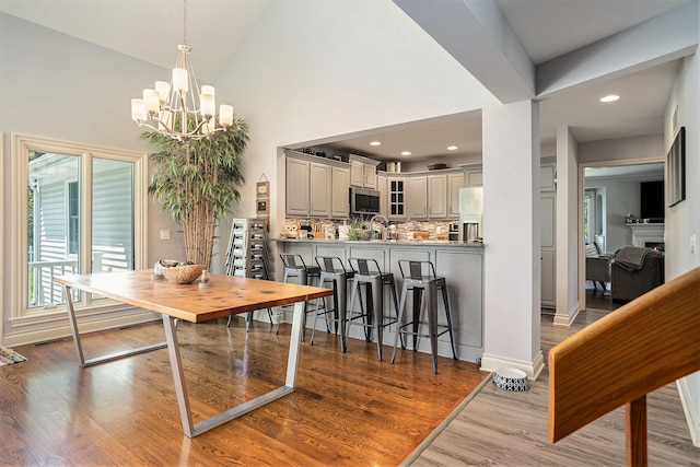 3225 Bronson Blvd, Kalamazoo, MI 49008 - dining space with a chandelier, wood finished floors, high vaulted ceiling, recessed lighting, and baseboards
