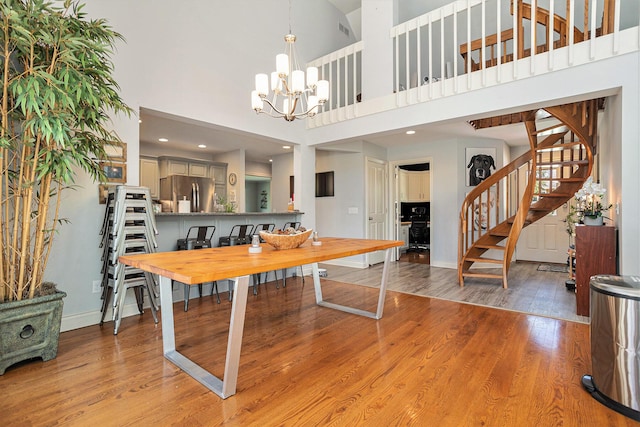 3225 Bronson Blvd, Kalamazoo, MI 49008 - dining space featuring stairs, a chandelier, wood finished floors, a towering ceiling, and baseboards