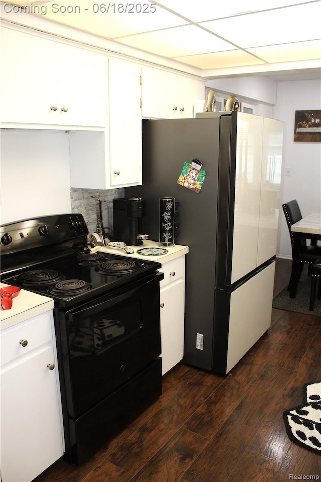 5095 Camborne Ct, Flint, MI 48504 - kitchen with black electric range, light countertops, dark wood-style flooring, white cabinetry, and freestanding refrigerator