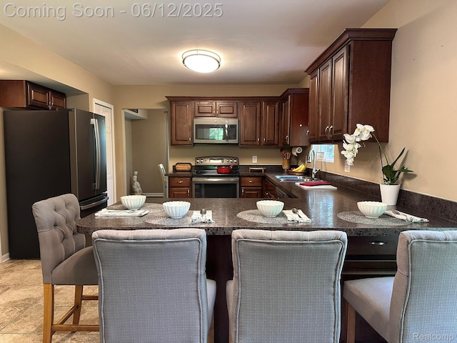 5836 Ewalt Rd, Imlay City, MI 48444 - kitchen with appliances with stainless steel finishes, dark countertops, a kitchen bar, and a peninsula