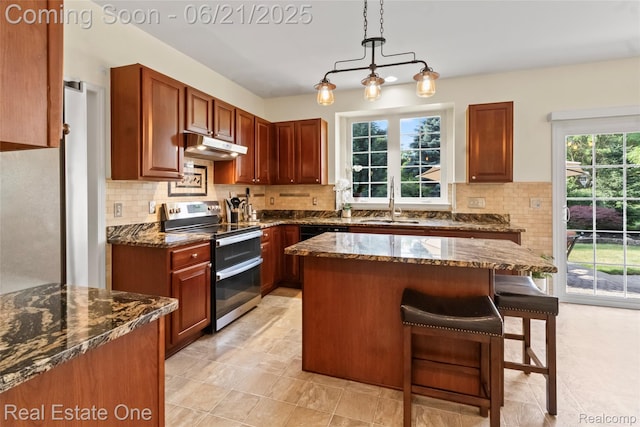7244 Millrock Ave, Shelby Twp, MI 48317 - kitchen with range with two ovens, dark stone counters, under cabinet range hood, tasteful backsplash, and a kitchen bar