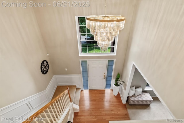 7244 Millrock Ave, Shelby Twp, MI 48317 - entrance foyer featuring a chandelier, a decorative wall, wood finished floors, wainscoting, and a towering ceiling