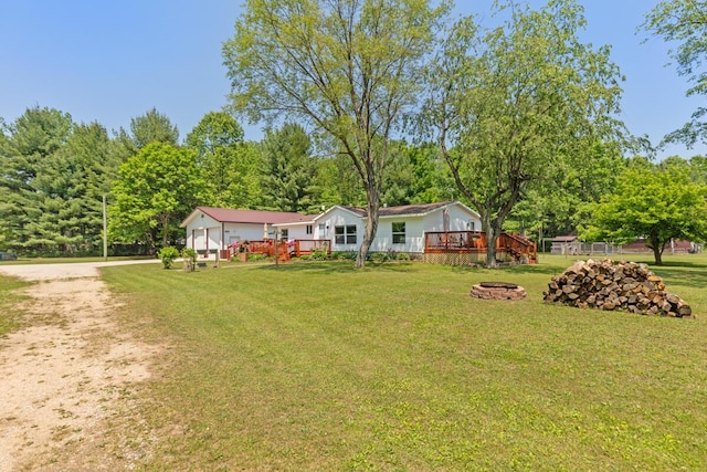 3858 S Chestnut Ave, Newaygo, MI 49337 - view of green lawn featuring a fire pit, a wooden deck, and driveway