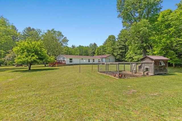 3858 S Chestnut Ave, Newaygo, MI 49337 - view of green lawn featuring exterior structure, an outbuilding, a garage, and view of wooded area