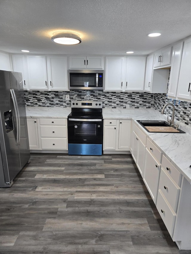 1420 Sweet St, Saginaw, MI 48602 - kitchen with stainless steel appliances, a sink, white cabinets, a textured ceiling, and decorative backsplash