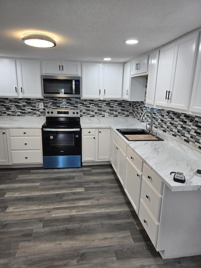 1420 Sweet St, Saginaw, MI 48602 - kitchen featuring appliances with stainless steel finishes, a sink, a textured ceiling, white cabinets, and decorative backsplash